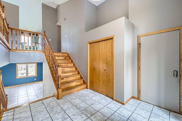 stairs with baseboards, tile patterned floors, and a high ceiling