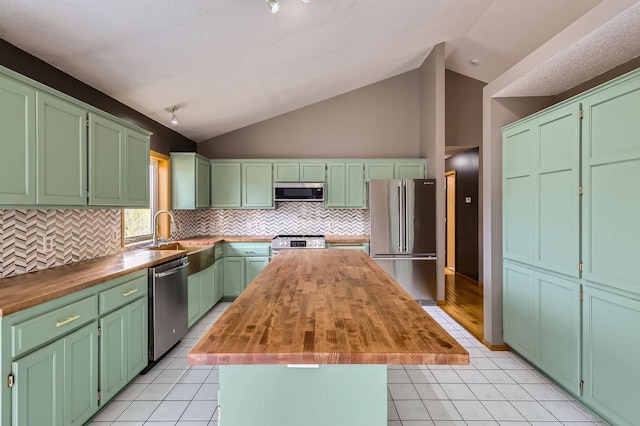 kitchen with lofted ceiling, butcher block countertops, a center island, a sink, and stainless steel appliances