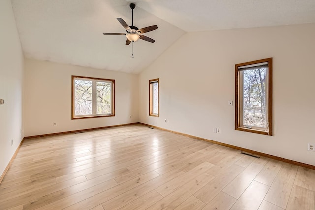 empty room with baseboards, a ceiling fan, a healthy amount of sunlight, and vaulted ceiling