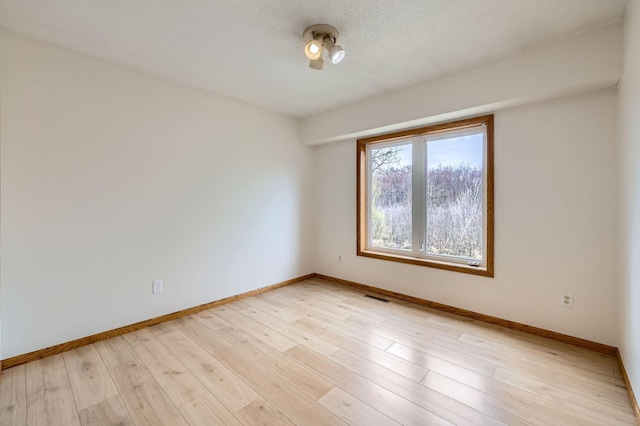 unfurnished room featuring baseboards, visible vents, and light wood finished floors