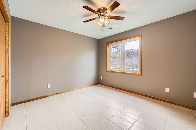 spare room with light tile patterned floors, baseboards, a ceiling fan, and a textured ceiling