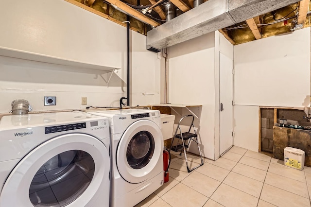 washroom featuring laundry area, washing machine and dryer, and light tile patterned floors