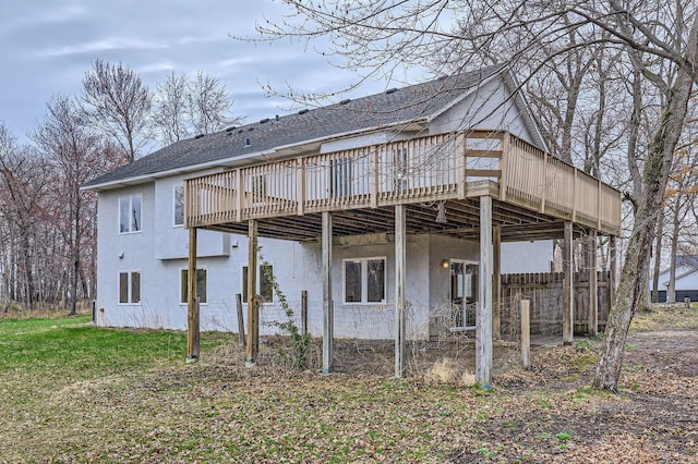 back of property with stucco siding, a shingled roof, and a wooden deck