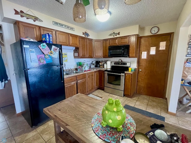 kitchen featuring light tile patterned floors, black appliances, a sink, and brown cabinets