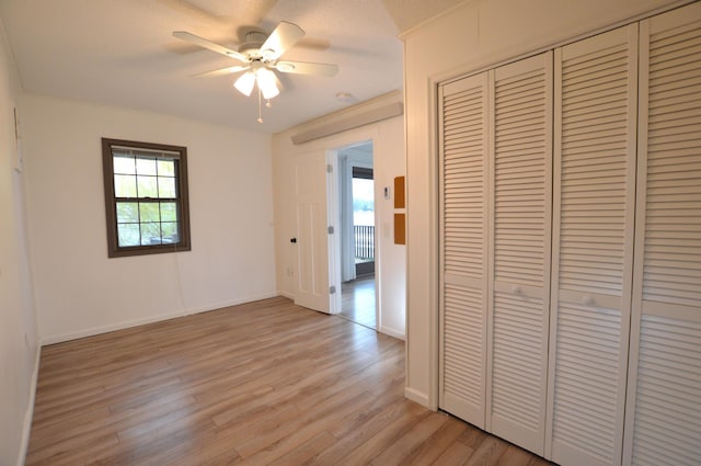 unfurnished bedroom featuring a closet, light wood-style flooring, ceiling fan, and baseboards