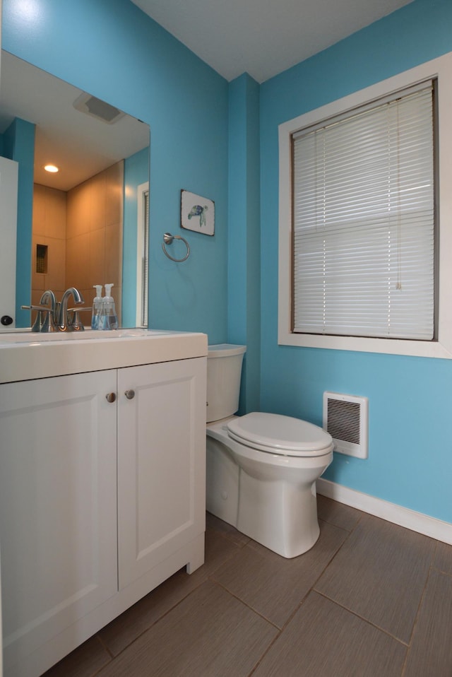 bathroom featuring vanity, toilet, baseboards, heating unit, and wood finished floors