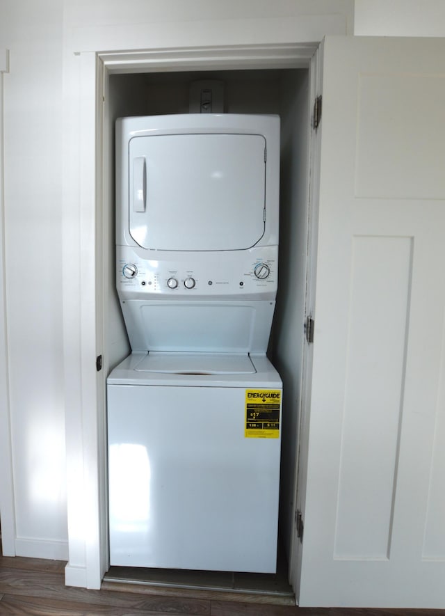 laundry room featuring laundry area, stacked washer / dryer, and wood finished floors