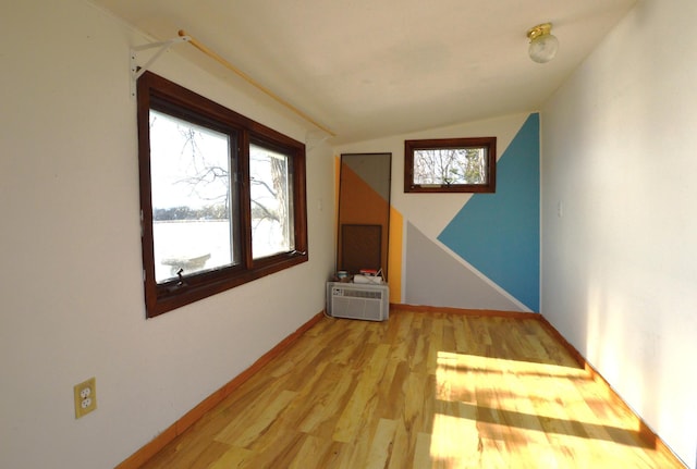 bonus room featuring baseboards, a wall mounted AC, vaulted ceiling, and light wood-type flooring