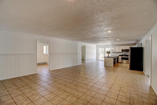 32290 US-71, Menahga, MN 56464 - unfurnished living room with a textured ceiling, healthy amount of natural light, a wainscoted wall, light tile patterned floors, and a baseboard heating unit