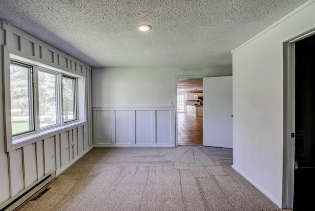 32290 US-71, Menahga, MN 56464 - unfurnished room with a baseboard radiator, a textured ceiling, carpet floors, a decorative wall, and wainscoting