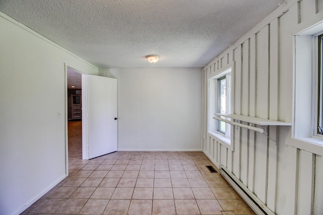32290 US-71, Menahga, MN 56464 - empty room with a baseboard radiator, light tile patterned flooring, a textured ceiling, and baseboards