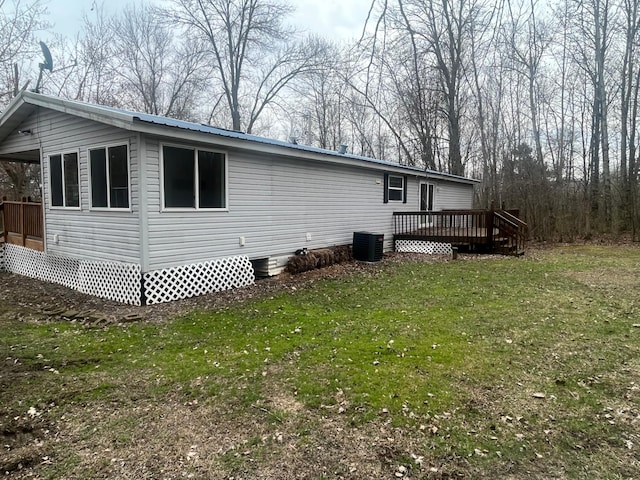 rear view of property with metal roof, a yard, central AC, and a deck