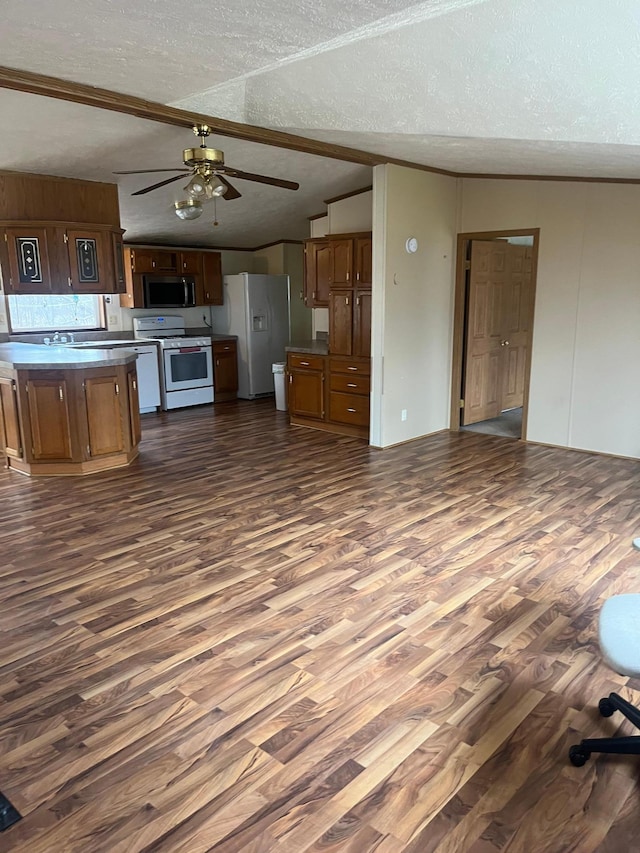 kitchen featuring a ceiling fan, a textured ceiling, dark wood finished floors, lofted ceiling, and white appliances