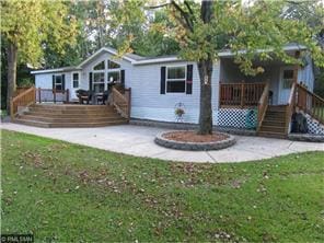 rear view of property featuring a wooden deck, stairs, a yard, and covered porch