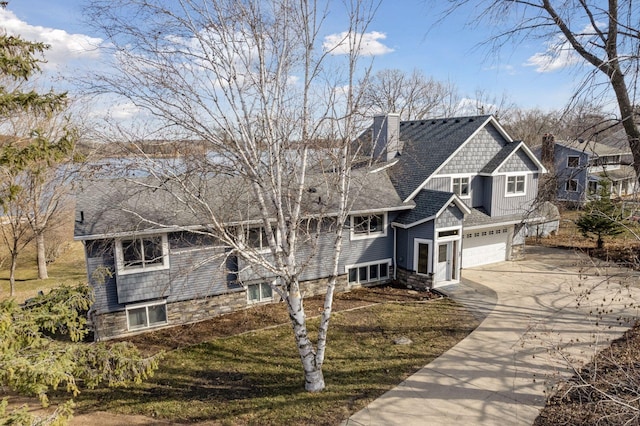 view of front of house with concrete driveway, a chimney, stone siding, and a garage