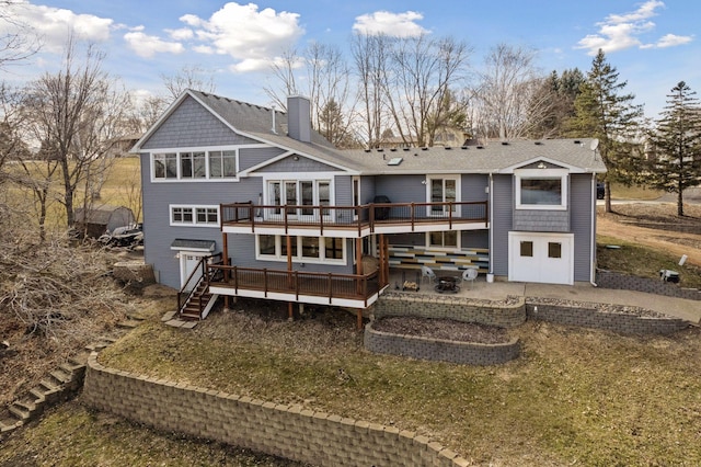 rear view of house with a wooden deck, roof with shingles, and a chimney