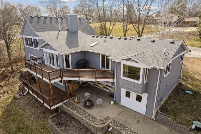 back of house with a patio, a shingled roof, a chimney, and a wooden deck