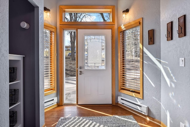entryway featuring baseboards, a textured wall, wood finished floors, and baseboard heating
