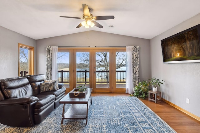 living area featuring ceiling fan, french doors, baseboards, wood finished floors, and lofted ceiling