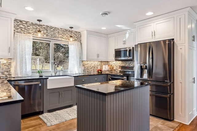 kitchen with decorative backsplash, white cabinetry, a sink, appliances with stainless steel finishes, and decorative light fixtures