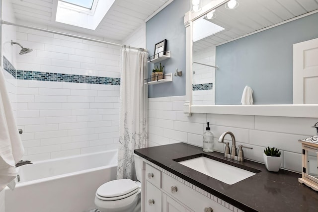 bathroom featuring a skylight, tile walls, shower / tub combo, vanity, and toilet