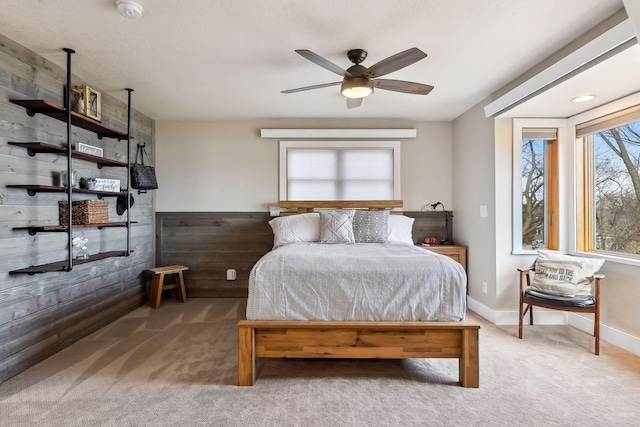 bedroom featuring baseboards, ceiling fan, carpet, and wood walls