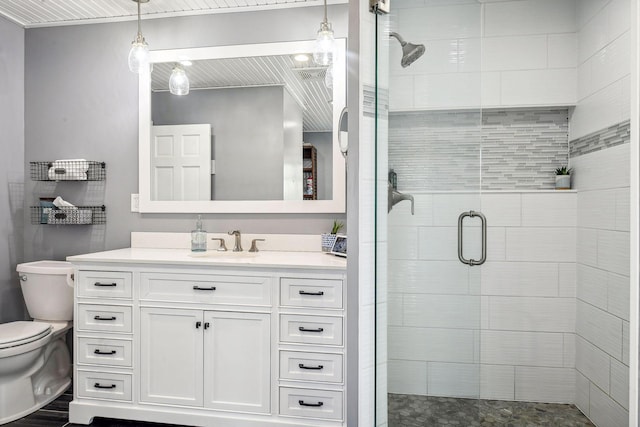 bathroom featuring toilet, a shower stall, and vanity