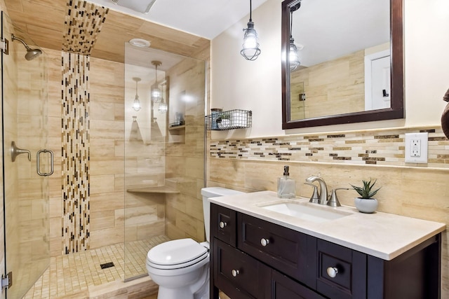 full bathroom with vanity, a shower stall, toilet, and tile walls