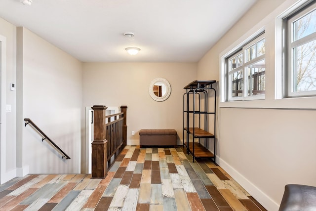 hall featuring baseboards, an upstairs landing, and wood finished floors