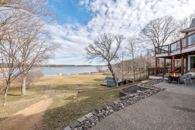 view of yard with a patio, a fire pit, and a deck with water view