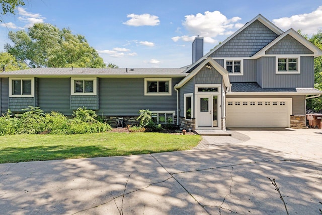 view of front of house with an attached garage, a front lawn, stone siding, a chimney, and driveway