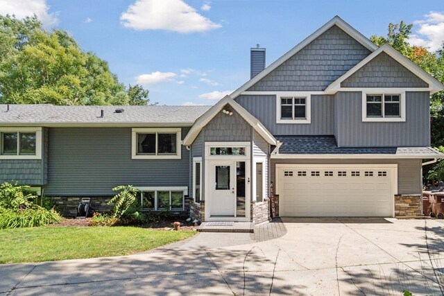 view of front facade with a chimney, a front lawn, concrete driveway, an attached garage, and stone siding