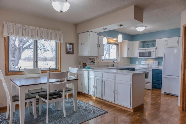 19447 County Road 1, Morris, MN 56267 - kitchen featuring white appliances, hanging light fixtures, white cabinetry, a peninsula, and light countertops