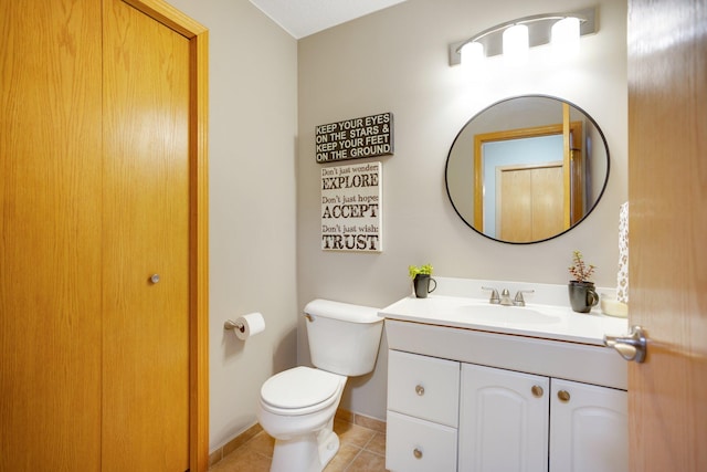 half bath featuring tile patterned floors, toilet, vanity, and baseboards