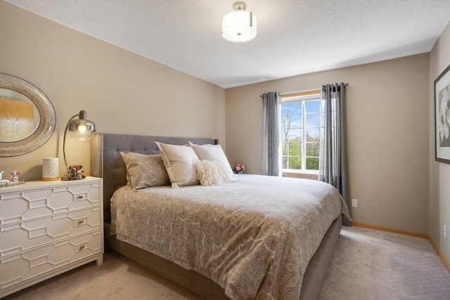 bedroom featuring light carpet, baseboards, and a textured ceiling