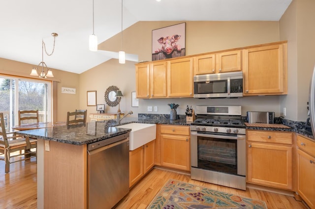kitchen with a sink, light brown cabinets, light wood-style floors, stainless steel appliances, and a peninsula