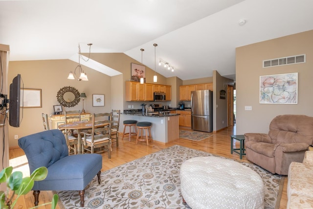 living room featuring visible vents, lofted ceiling, and light wood-type flooring