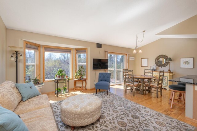 living area featuring baseboards, vaulted ceiling, and light wood finished floors