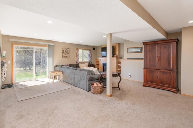 living area featuring light colored carpet, recessed lighting, baseboards, and a glass covered fireplace