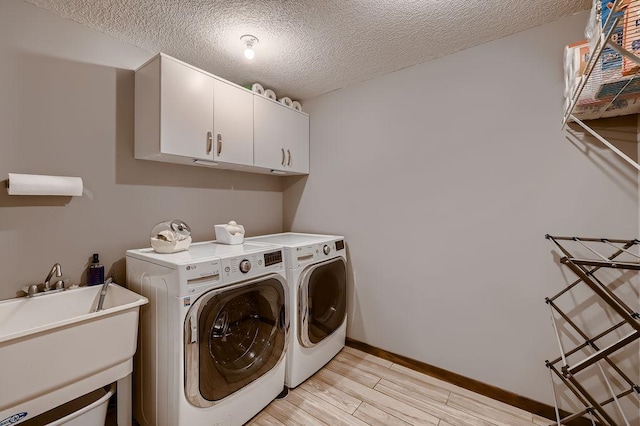 334 143rd Ave NW, Andover, MN 55304 - clothes washing area featuring washer and clothes dryer, cabinet space, light wood finished floors, baseboards, and a textured ceiling