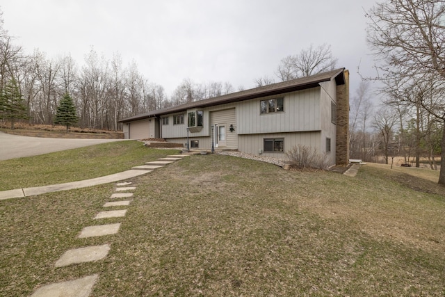 raised ranch with a front lawn, driveway, and an attached garage