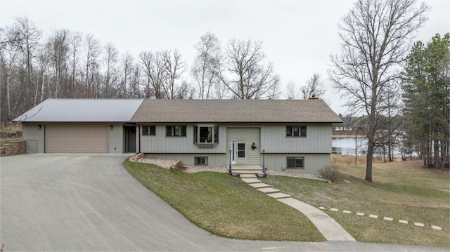 raised ranch featuring a front yard, aphalt driveway, and an attached garage