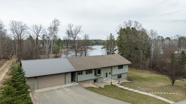 view of front of house with a chimney, driveway, roof with shingles, a front yard, and an attached garage