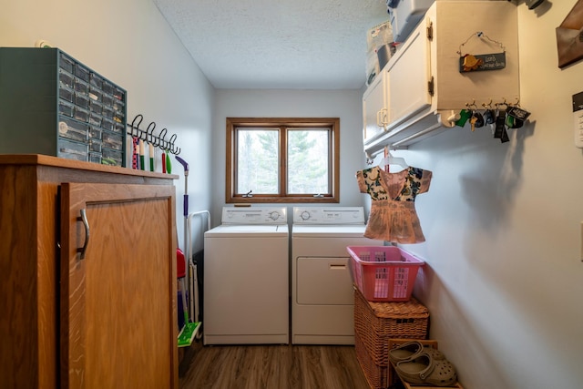 laundry area with a textured ceiling, washing machine and clothes dryer, cabinet space, and dark wood-style floors
