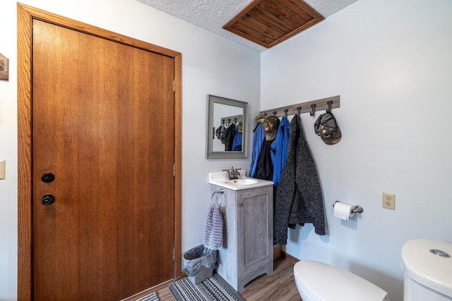 half bath with wood finished floors, toilet, and vanity