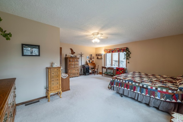 bedroom with visible vents, a ceiling fan, carpet floors, and a textured ceiling