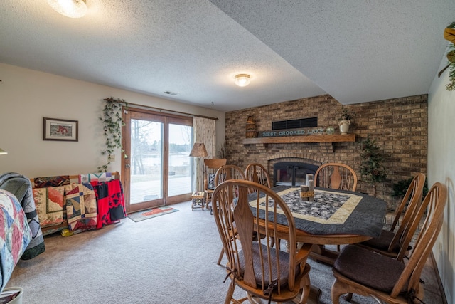 carpeted dining room featuring visible vents, a textured ceiling, and a fireplace