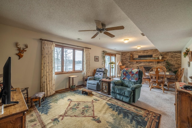 carpeted living area featuring a textured ceiling, visible vents, a ceiling fan, and a brick fireplace
