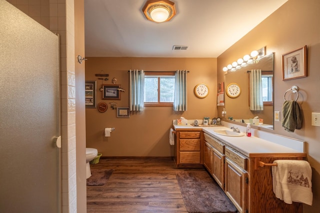 bathroom with vanity, toilet, visible vents, a shower, and wood finished floors