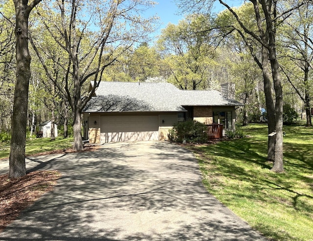 view of front of home with asphalt driveway, a chimney, an attached garage, a front lawn, and a shingled roof